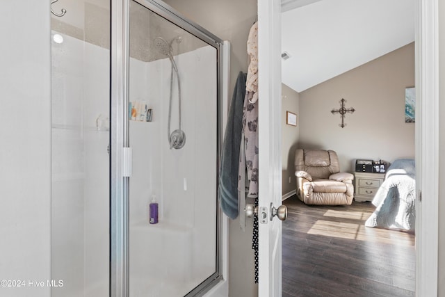 bathroom featuring hardwood / wood-style flooring, a shower with shower door, and lofted ceiling