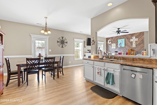 kitchen with dishwasher, ceiling fan with notable chandelier, sink, hanging light fixtures, and tasteful backsplash