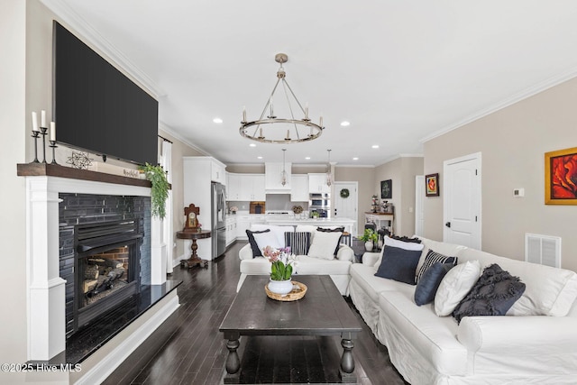 living room with a fireplace with raised hearth, a chandelier, recessed lighting, visible vents, and dark wood-style floors