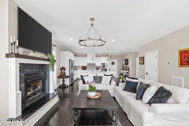 living room with a fireplace, dark hardwood / wood-style flooring, crown molding, and a chandelier