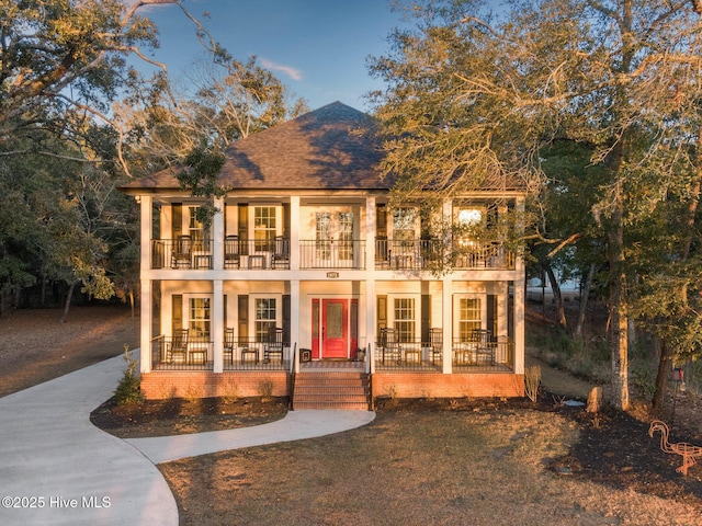 view of front of house featuring covered porch, a shingled roof, stucco siding, and a balcony