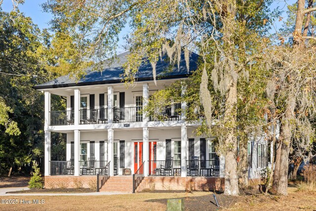 back of house with a porch, french doors, a balcony, and roof with shingles