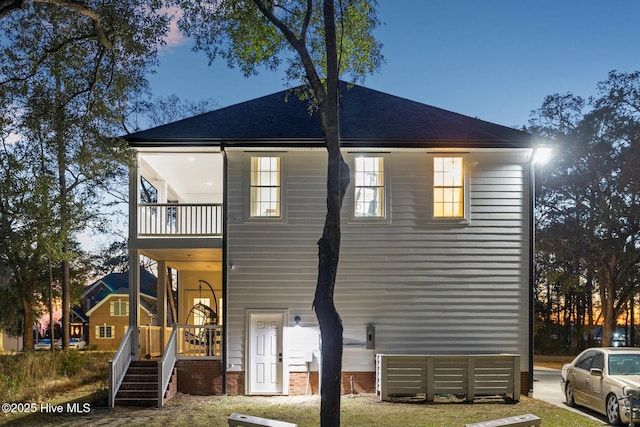 rear view of property with a shingled roof and a balcony