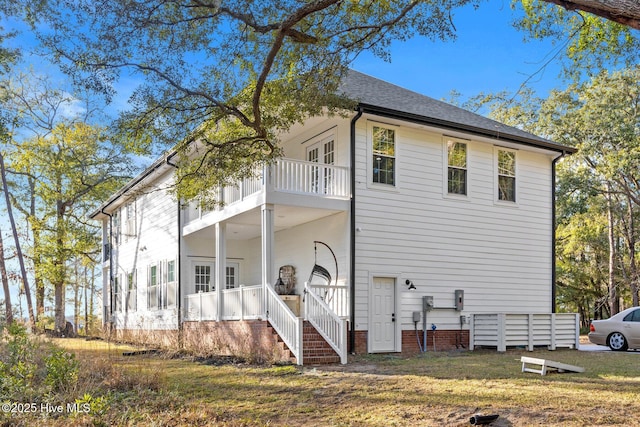 rear view of house featuring a yard and a balcony