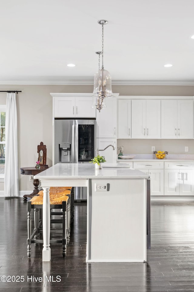 kitchen with white cabinetry, a kitchen bar, decorative light fixtures, a kitchen island with sink, and dark hardwood / wood-style flooring