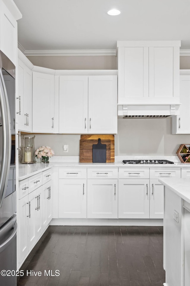 kitchen with appliances with stainless steel finishes, light countertops, white cabinets, ornamental molding, and recessed lighting