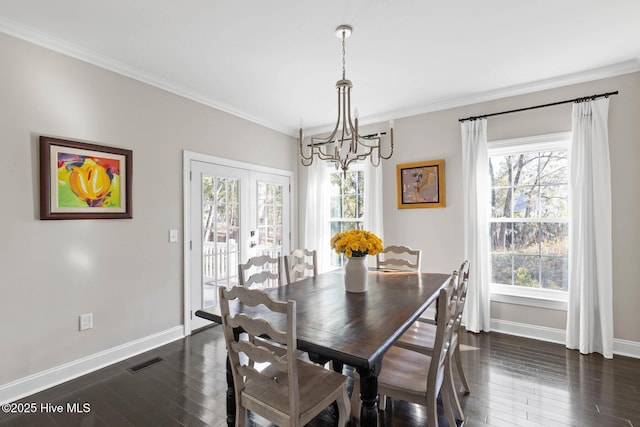 dining area featuring plenty of natural light, dark hardwood / wood-style floors, ornamental molding, and an inviting chandelier