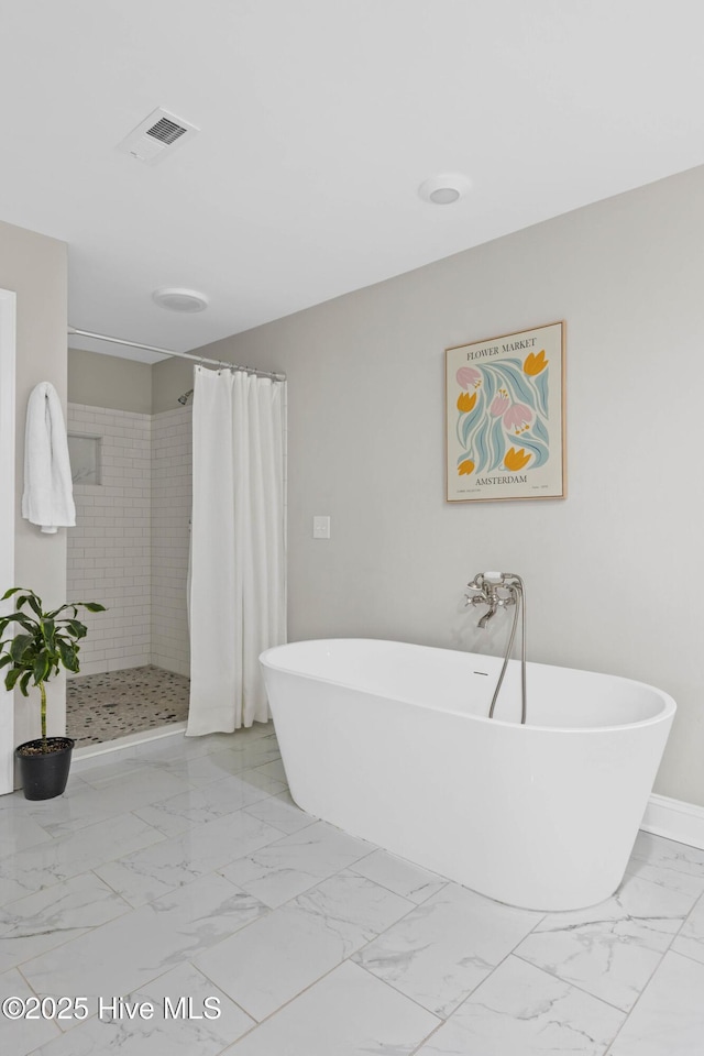 bathroom with marble finish floor, a freestanding tub, baseboards, visible vents, and a stall shower
