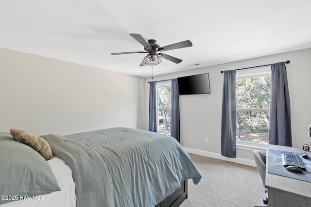 bedroom featuring light colored carpet, a ceiling fan, baseboards, and multiple windows