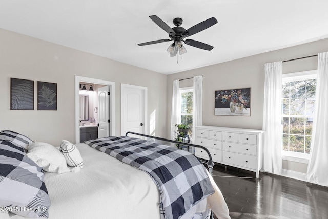bedroom with baseboards, ensuite bathroom, ceiling fan, and dark wood-type flooring