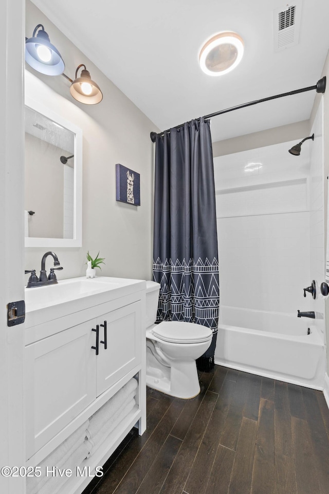 bathroom with visible vents, vanity, wood finished floors, shower / bath combination with curtain, and toilet