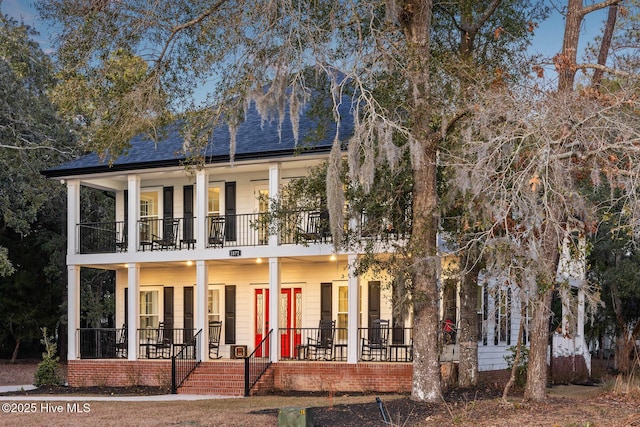 back of property featuring a shingled roof, a balcony, and covered porch