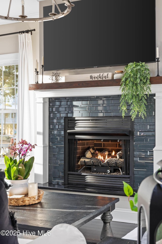 details featuring a warm lit fireplace and wood finished floors