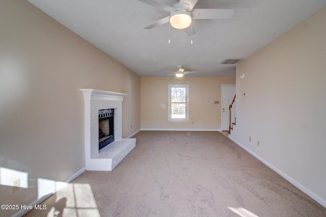 unfurnished living room featuring a textured ceiling, a brick fireplace, light colored carpet, and ceiling fan