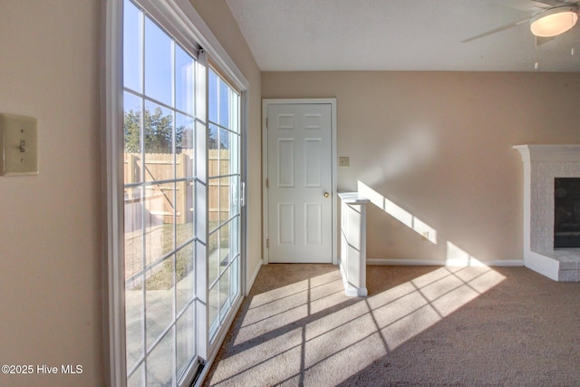 interior space featuring light carpet, ceiling fan, and a brick fireplace