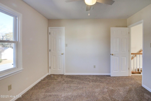 unfurnished room featuring ceiling fan, light colored carpet, and plenty of natural light