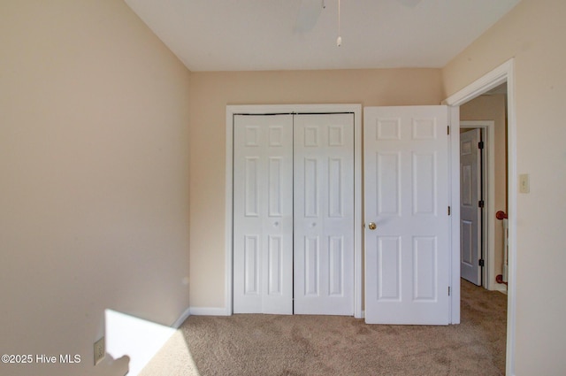 unfurnished bedroom featuring light carpet, ceiling fan, and a closet