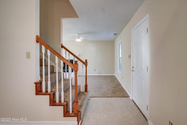 foyer entrance with ceiling fan and light colored carpet