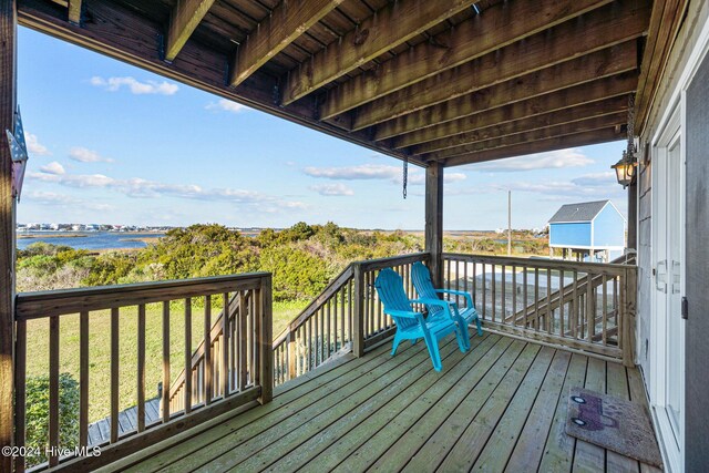 deck at dusk featuring a water view