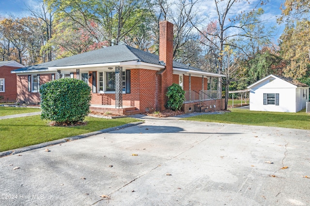 view of front facade featuring covered porch, a front lawn, and a storage shed