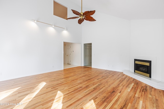 unfurnished living room with ceiling fan, high vaulted ceiling, and light hardwood / wood-style floors