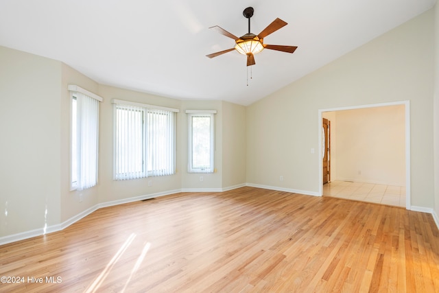 spare room with light hardwood / wood-style floors, vaulted ceiling, and ceiling fan