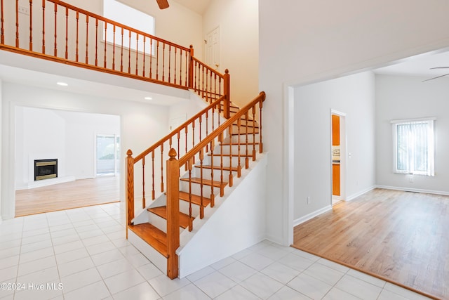 stairway featuring a towering ceiling, hardwood / wood-style flooring, and ceiling fan