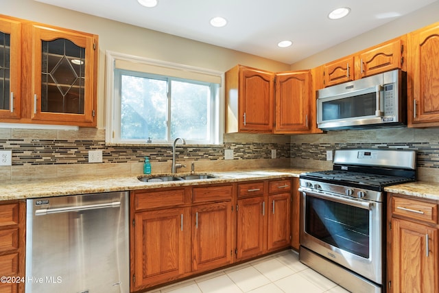 kitchen featuring backsplash, light stone counters, sink, and appliances with stainless steel finishes