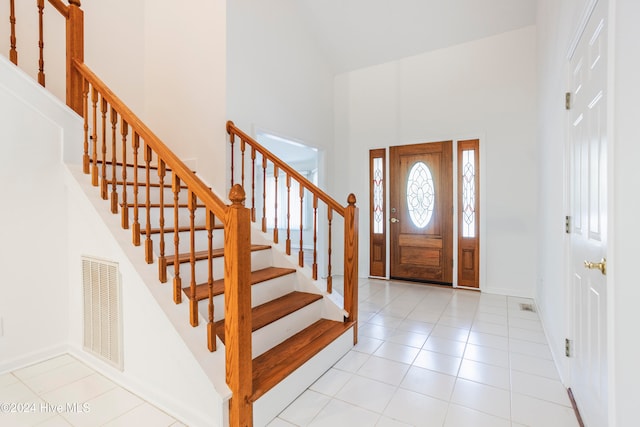 entrance foyer featuring light tile patterned flooring and a towering ceiling