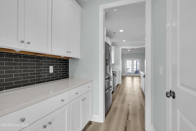 interior space featuring tasteful backsplash, light wood finished floors, crown molding, light stone countertops, and white cabinetry