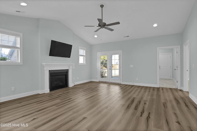 unfurnished living room featuring wood finished floors, visible vents, baseboards, a tile fireplace, and vaulted ceiling