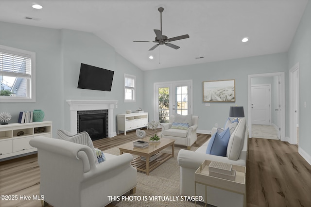 living room featuring vaulted ceiling, wood finished floors, and a tile fireplace