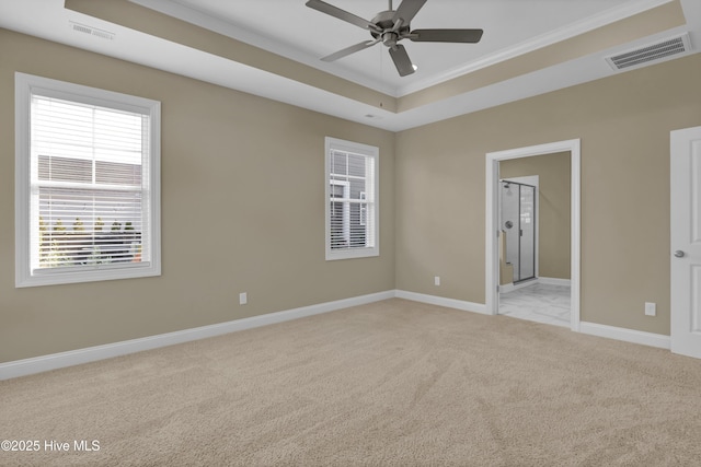 spare room featuring a tray ceiling, visible vents, baseboards, and light colored carpet