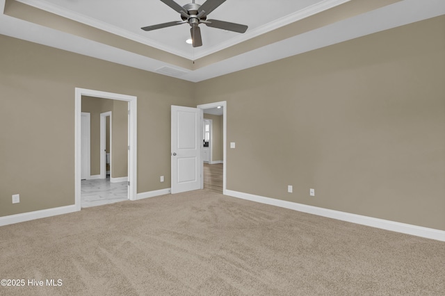 unfurnished bedroom with a ceiling fan, baseboards, crown molding, light colored carpet, and a raised ceiling