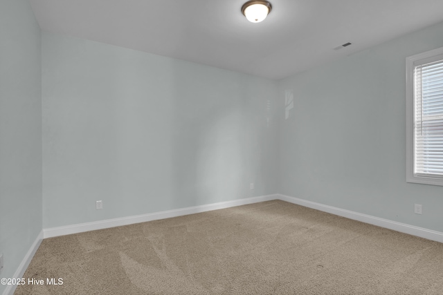 carpeted spare room featuring plenty of natural light, visible vents, and baseboards