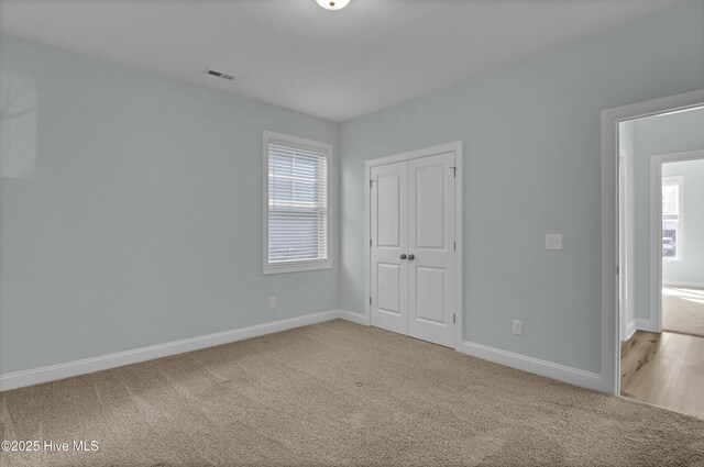 unfurnished bedroom featuring a closet, multiple windows, baseboards, and carpet floors