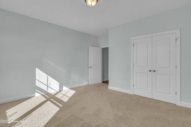 unfurnished bedroom with baseboards, carpet floors, and a closet