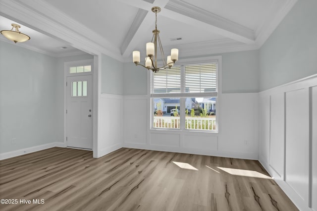 unfurnished dining area featuring beam ceiling, a notable chandelier, crown molding, and hardwood / wood-style floors