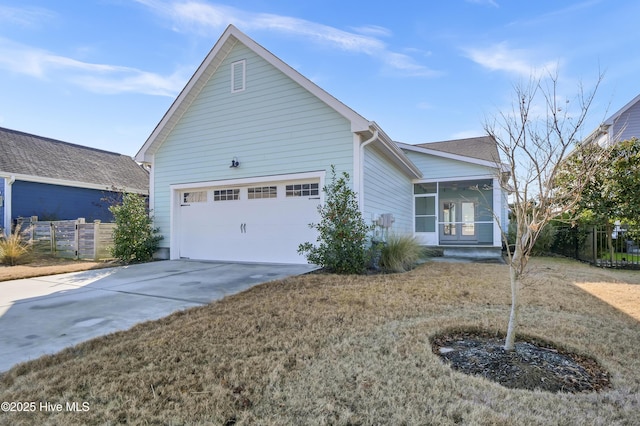 view of front of property with an attached garage, concrete driveway, a sunroom, and fence