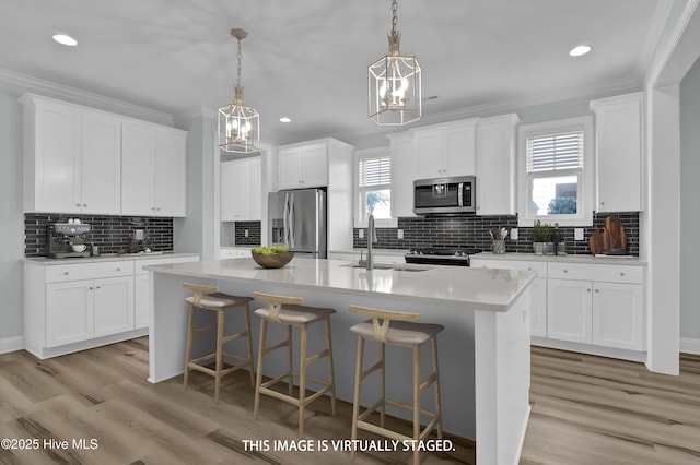 kitchen featuring a wealth of natural light, appliances with stainless steel finishes, a kitchen island with sink, and crown molding