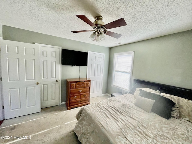 carpeted bedroom with ceiling fan and a textured ceiling