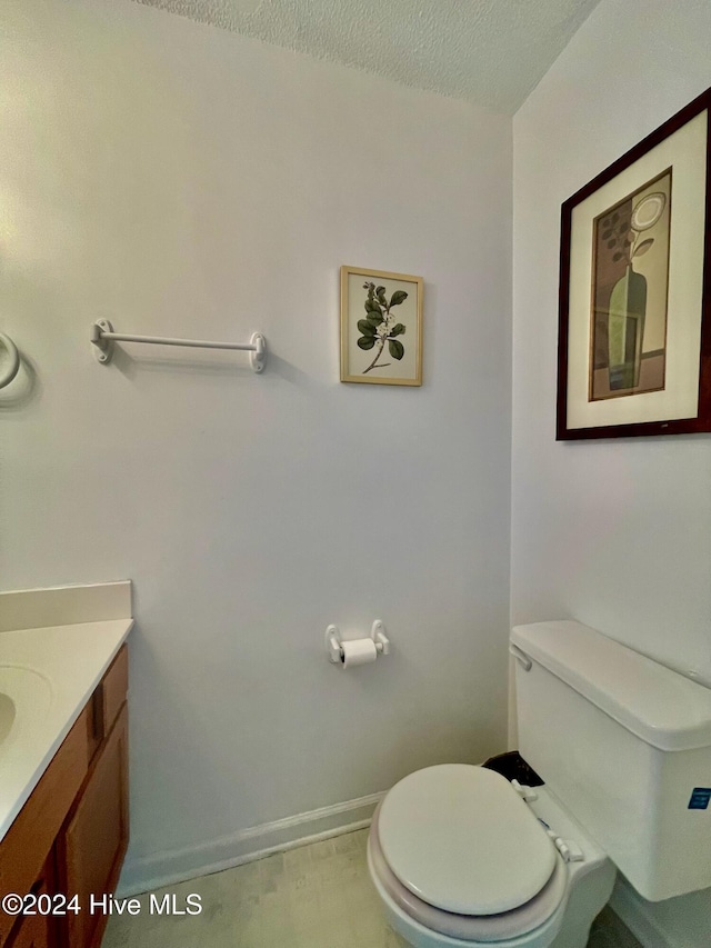 bathroom with vanity, toilet, and a textured ceiling