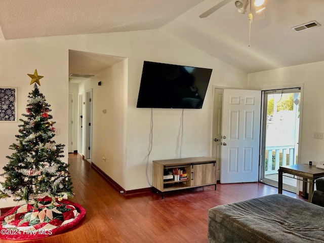 living room with ceiling fan, dark hardwood / wood-style flooring, lofted ceiling, and a textured ceiling