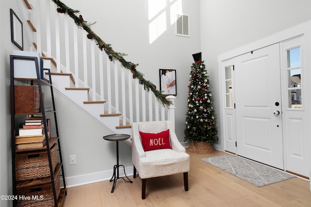 entryway with hardwood / wood-style floors and a towering ceiling