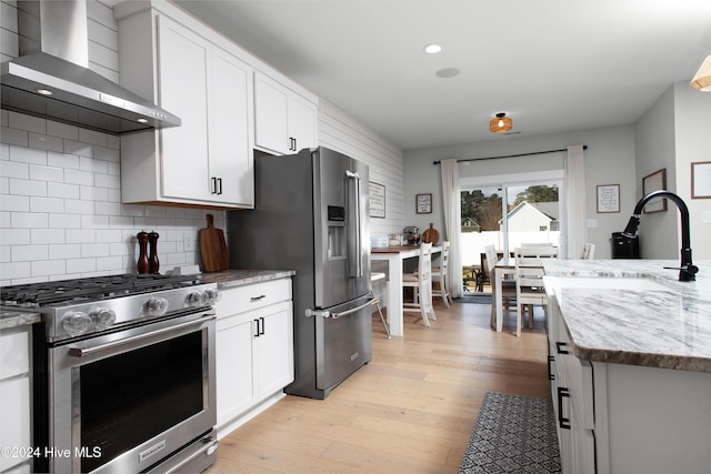 kitchen featuring light hardwood / wood-style flooring, white cabinetry, high quality appliances, and wall chimney range hood