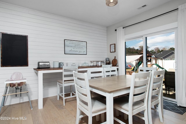 dining space with wooden walls and light hardwood / wood-style flooring