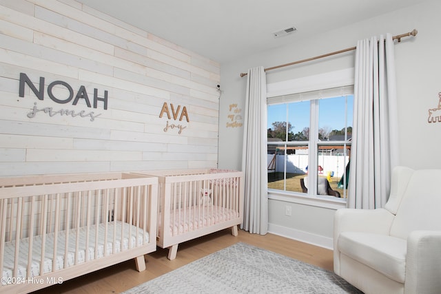 bedroom featuring hardwood / wood-style floors and a crib