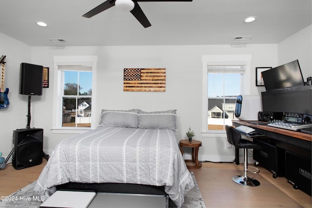 bedroom featuring ceiling fan, light hardwood / wood-style flooring, and multiple windows