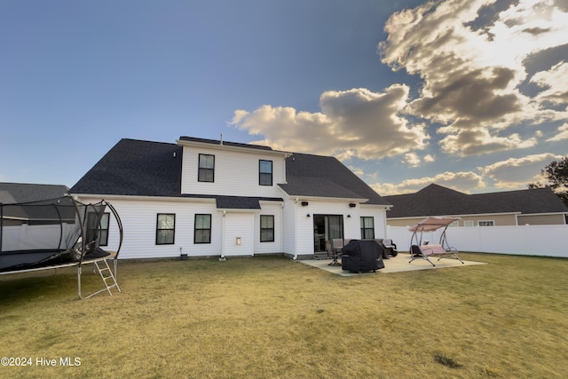 back of house with a patio area, a yard, and a trampoline