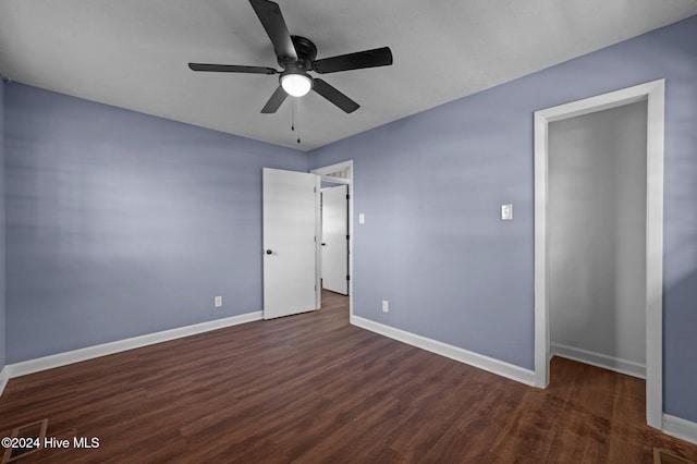 unfurnished bedroom with ceiling fan and dark wood-type flooring